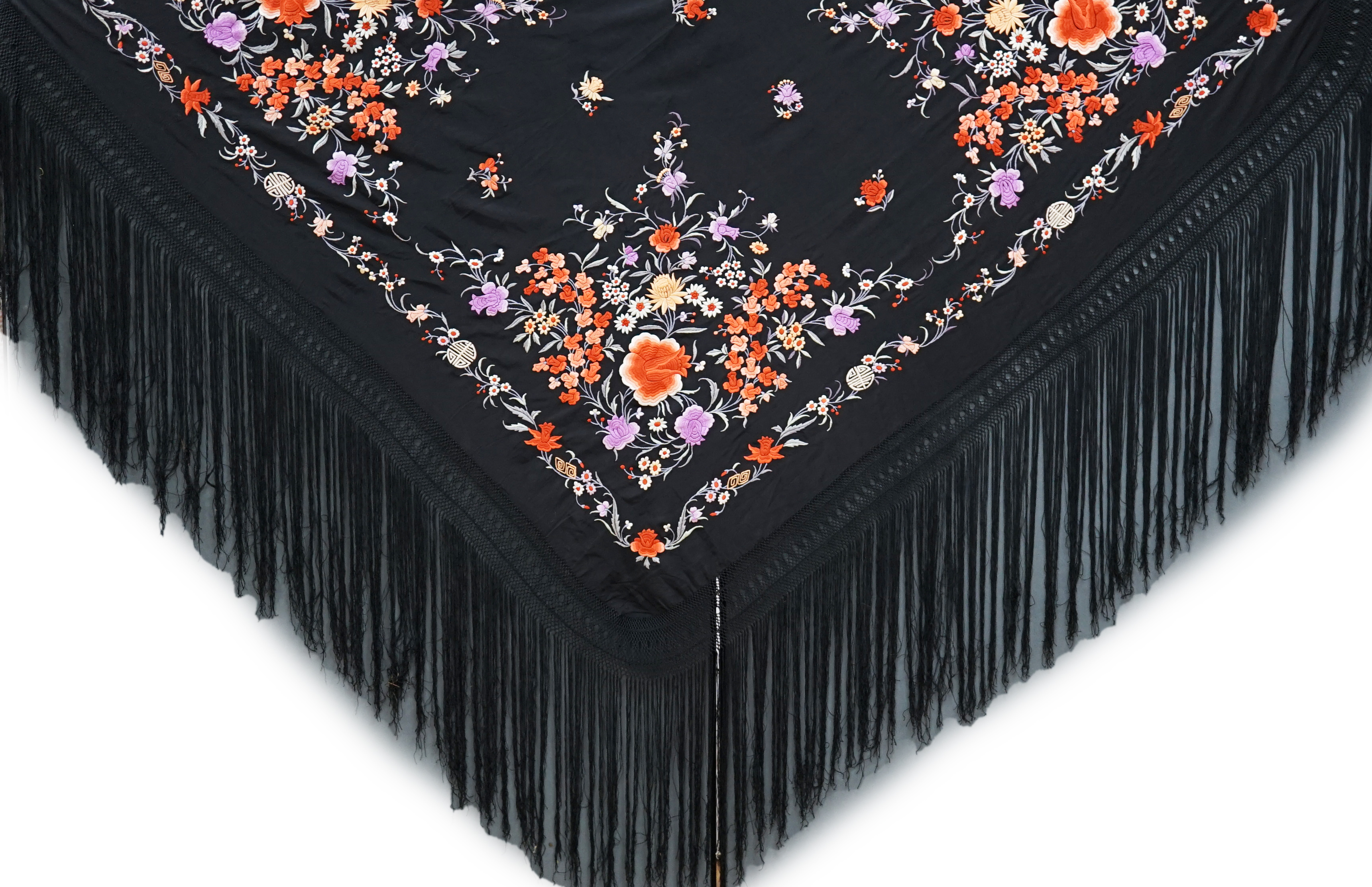 A late 19th / early 20th century Chinese black silk shawl, with polychrome silk embroidered flowers in green, red, orange, lilac, yellow and white, the centre embroidered with, sprigs of multi-coloured flowers, the four